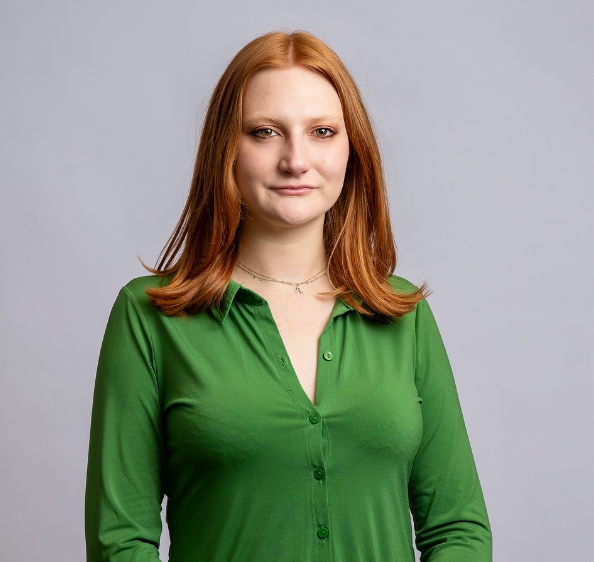 Red haired female wearing green button up shirt and necklace with letter A pendant