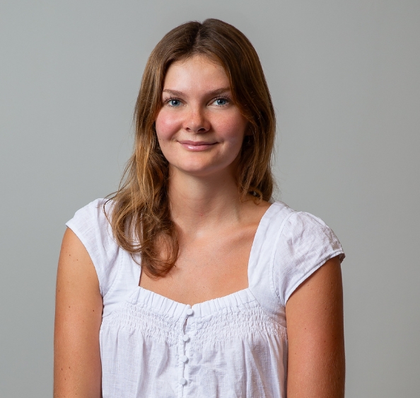 Female with shoulder length brown hair in white short sleeved shirt